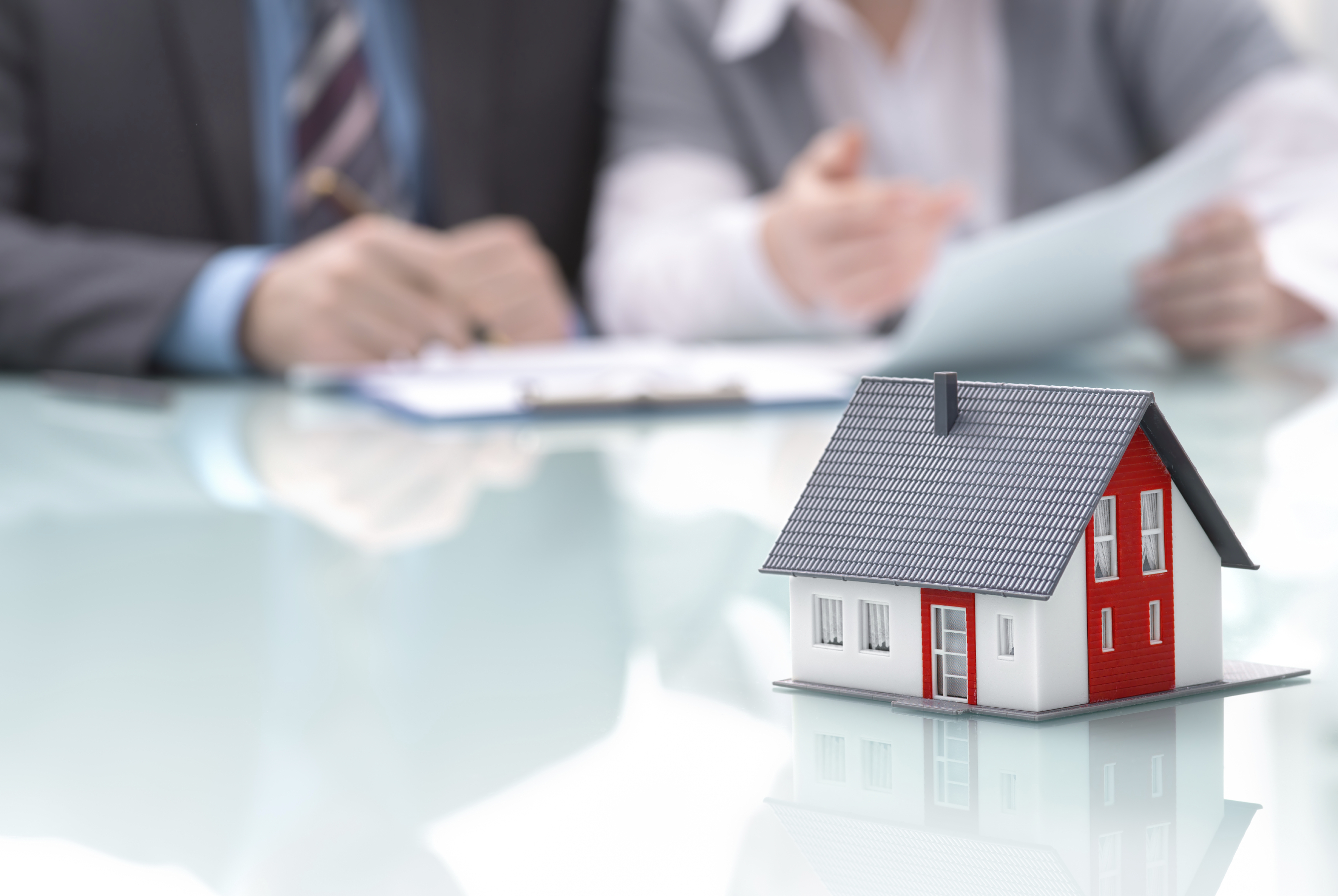 Businessman signs contract behind home architectural model